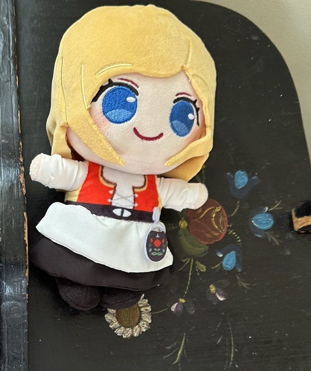 Blonde BestaJuni doll with blue eyes wearing a red bunad